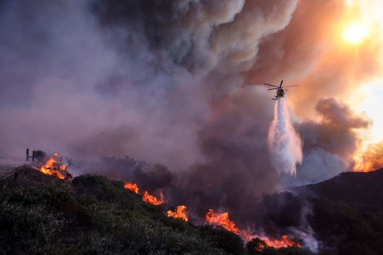 Water is dropped by helicopter on the advancing Palisades Fire