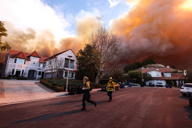 Image: Firefighters run as a brush fire burns in Pacific Palisades, Calif., on Jan. 7, 2025.