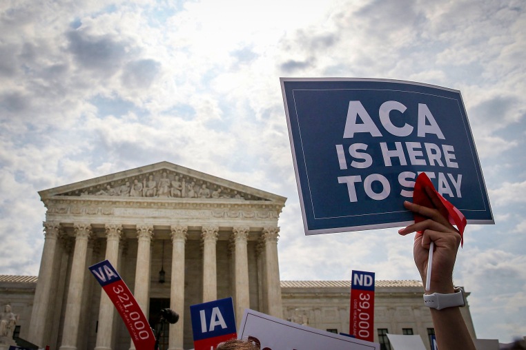 A sign is held up that reads "ACA Is Here To Stay" front of the U.S. Supreme Court.