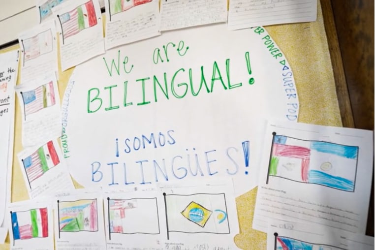 A sign says "We are bilingual! Somos bilingues!" on a classroom board