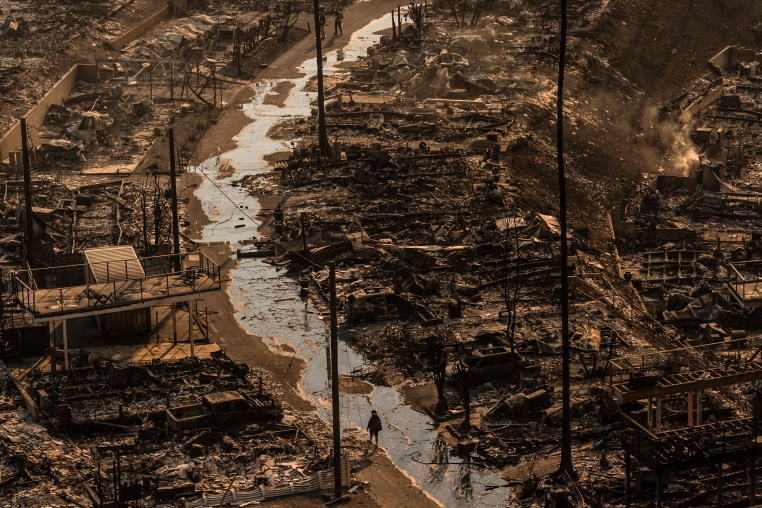 A person walks amid the destruction left behind by the Palisades Fire