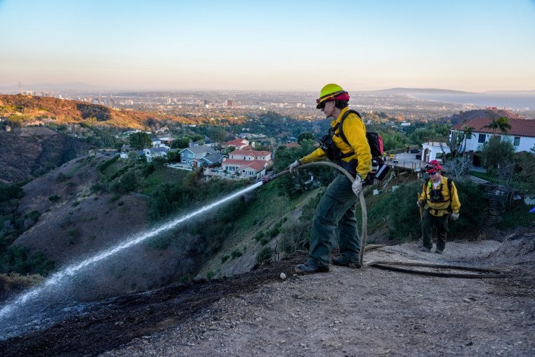 A Firefighter sprays water over a hillside