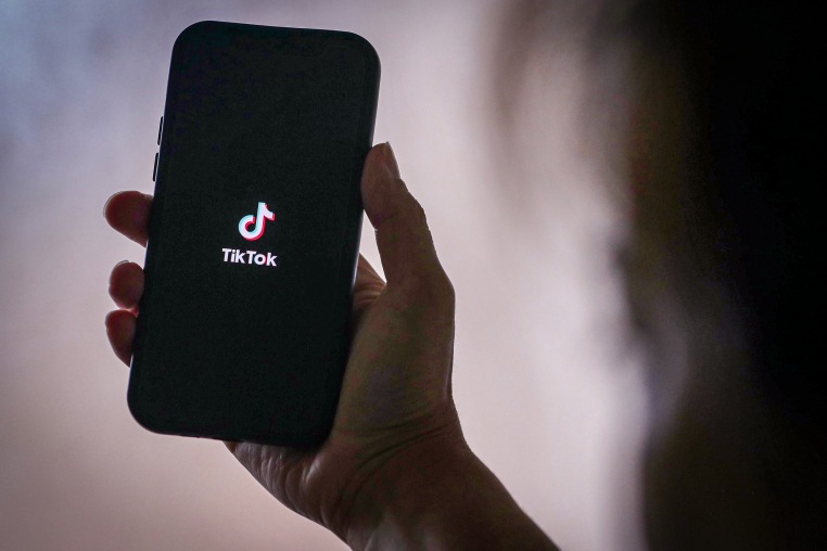 A person holds a phone with the TikTok logo.