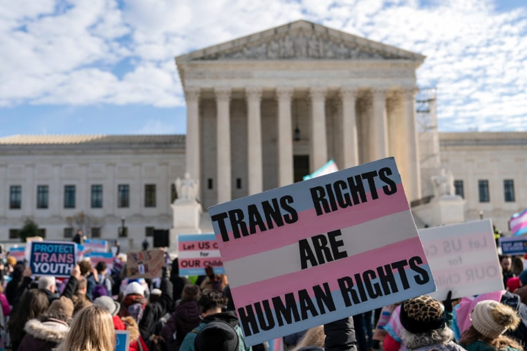 Transgenders rights supporters rally outside of the Supreme Court, a sign is held saying "Trans Rights Are Human Rights"