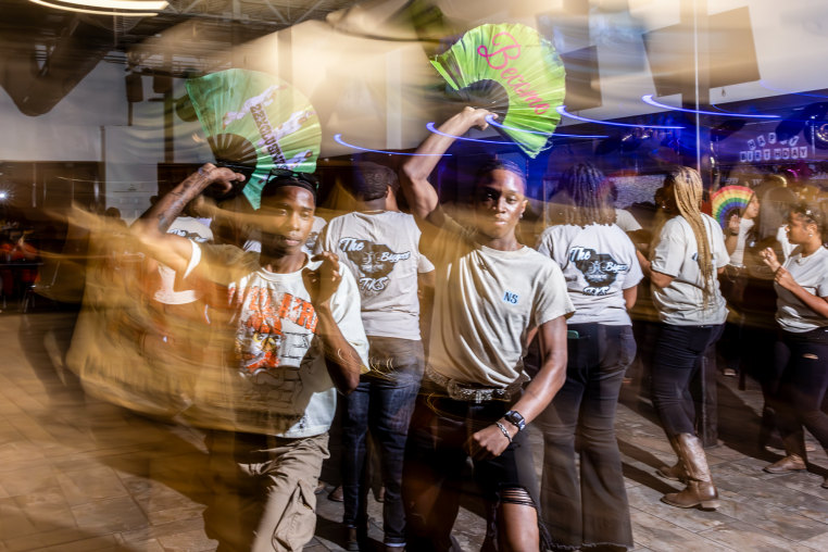 Quinton Dais, left, and Ny’Sean Isaac line dance holding fans