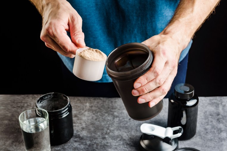 Hands add protein to a shaker.