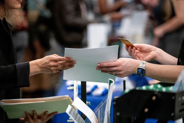 An attendee hands a resume to a recruiter at a job fair hiring event in Sacramento, Calif., on Feb. 27, 2025. 