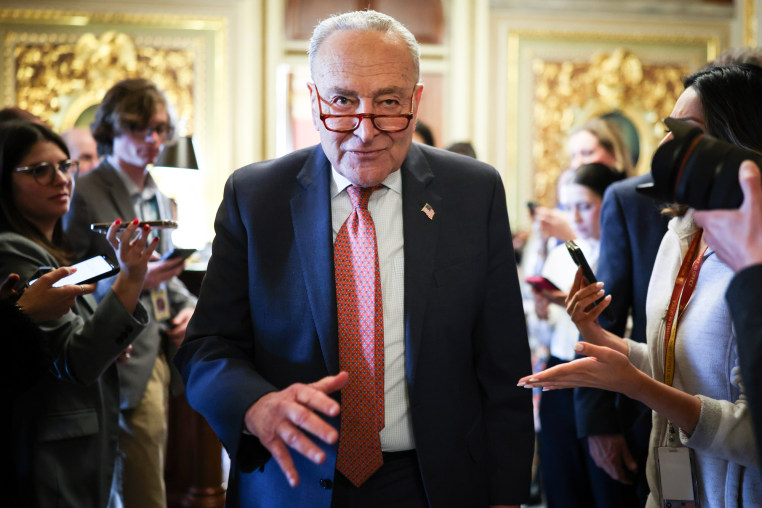 Chuck Schumer walks through a crowd of reporters