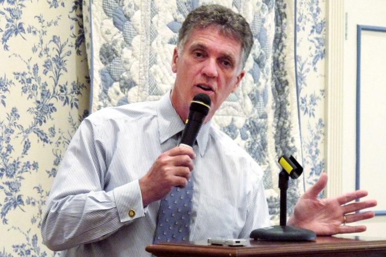 Dave Weldon speaks into a microphone at a podium