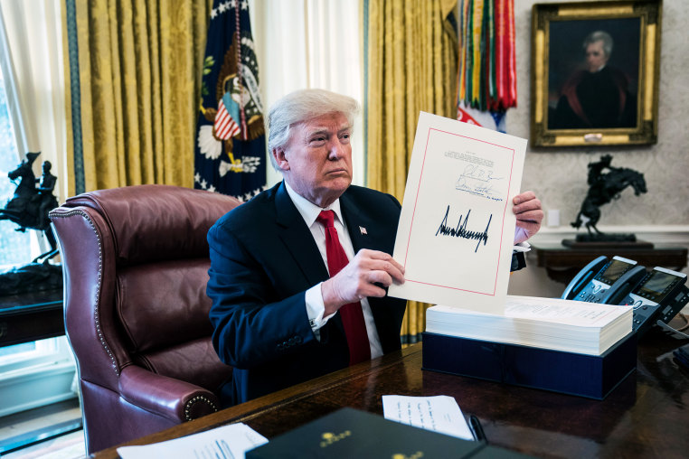 Donald Trump holds up the signed bill 