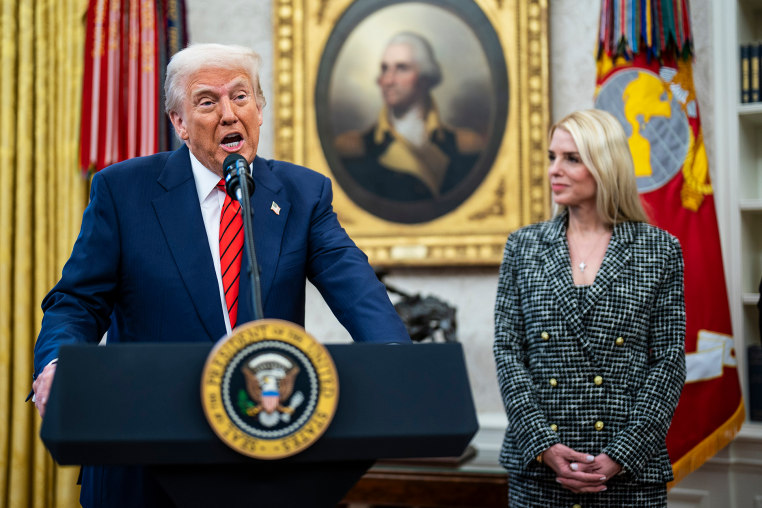 Donald Trump, left, speaks at a podium next to Pam Bondi, who watches