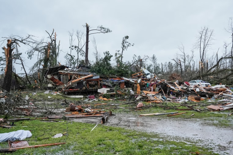 A storm damaged home outside, debris and fallen branches everywhere on the lawn