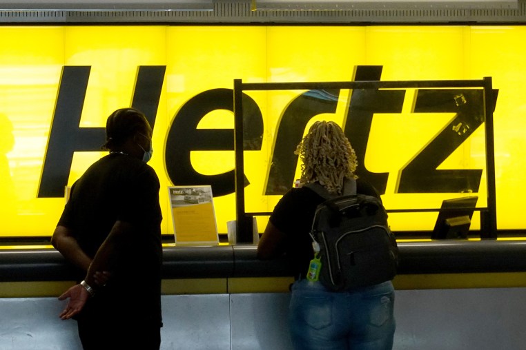 People stand at a Hertz car rental counter