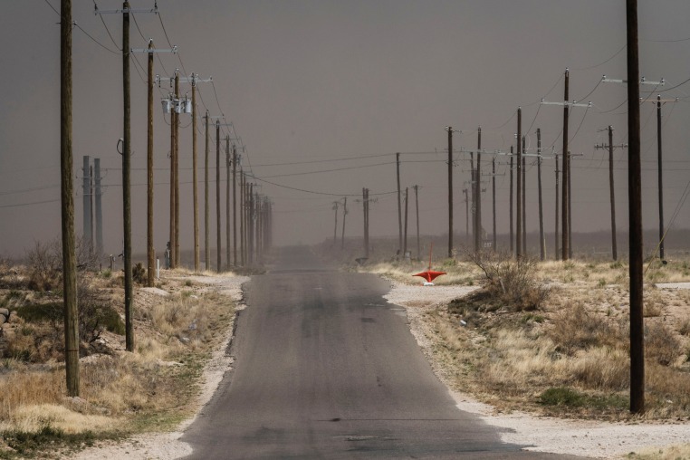 A dust storm is seen from a road lined with power lines