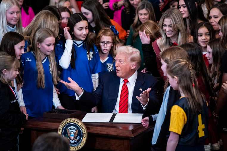 President Donald Trump is surrounded by girl athletes as he signs an executive order banning transgender athletes from participating in women's sports.