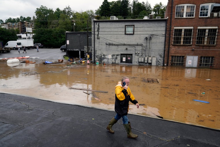 A man walks near a flooded area near the Swannanoa river