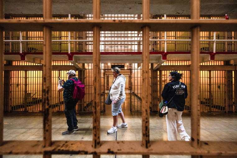 Visitors walk through a cell block of a prison