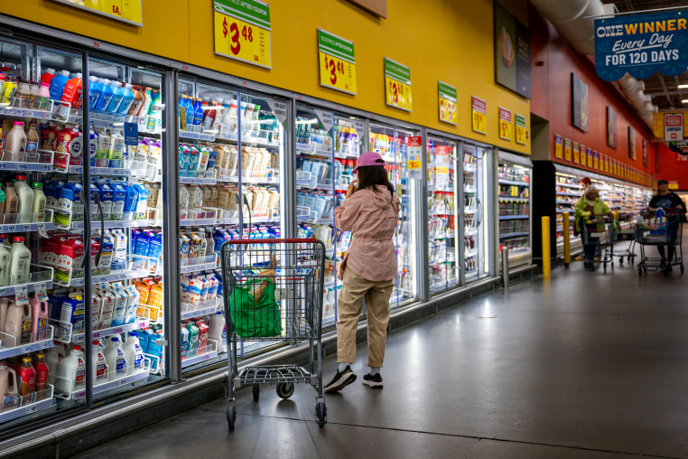 A customer browses refrigerated drinks in a grocery store.