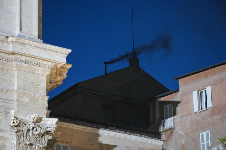 Black smoke is seen from the chimney of the Sistine Chapel at night