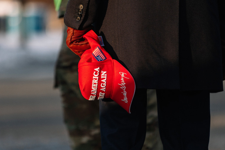 A Trump supporter holding a MAGA hat 