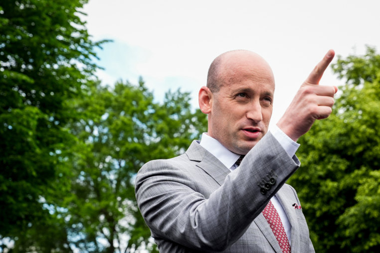 Stephen Miller points while speaking, stands outside