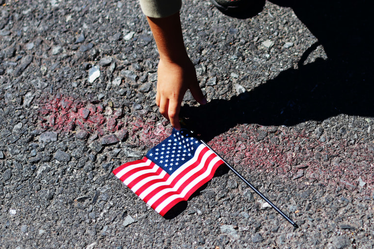 A boy reaches over to pick up a U.S. flag