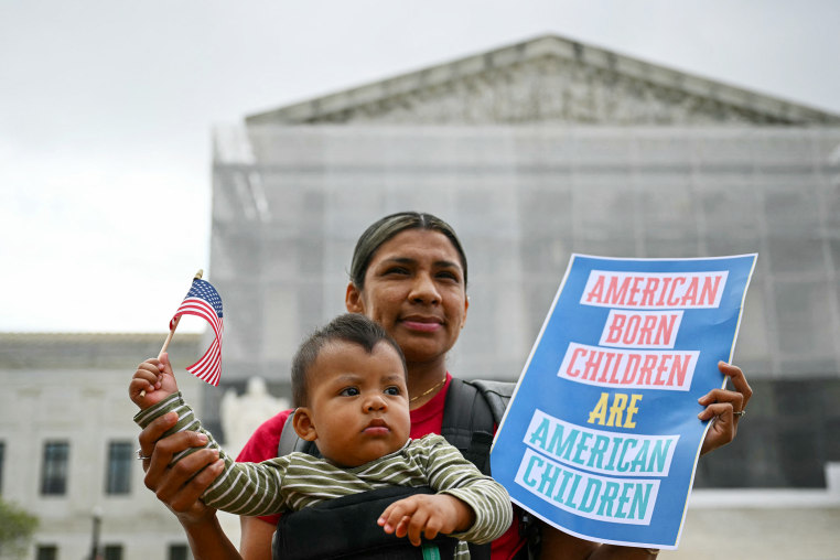 Olga Urbina holds a sign that reads "American Born Children are American Children" as her son Aers holds an American flag.