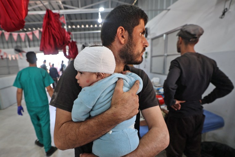A man holds a wounded child after receiving treatment at Al-Awda Hospital in central Gaza.