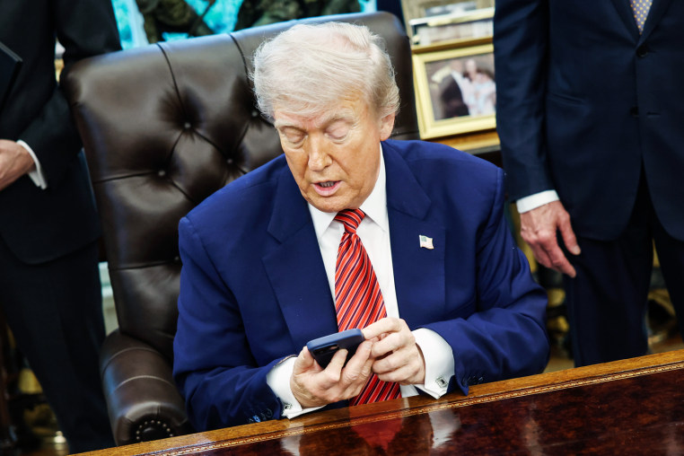 Donald Trump uses his cellphone at his desk in the Oval Office