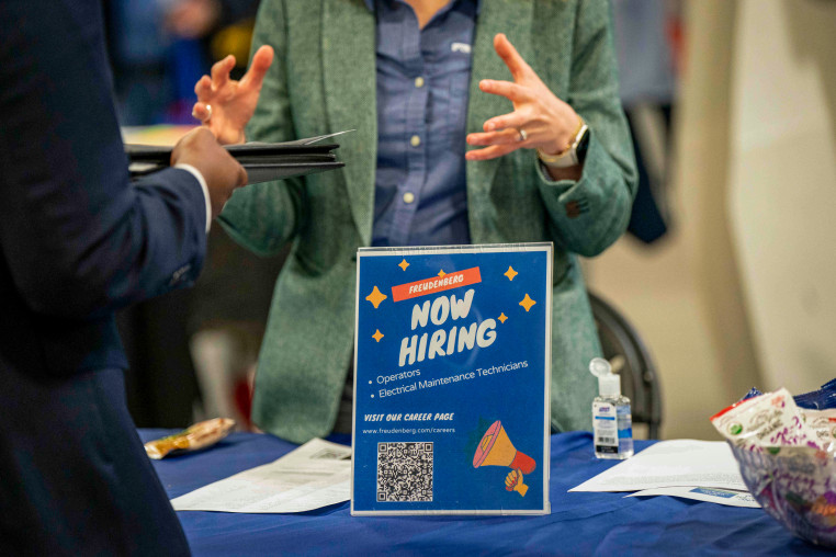 A "Now Hiring" sign at a job and resource fair.