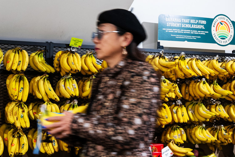 A shopper in front of a display of bananas.