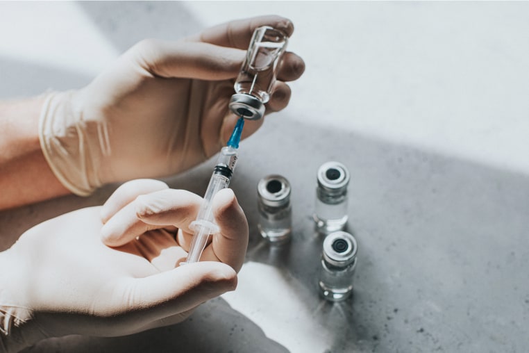 Hands holding a vial and needle