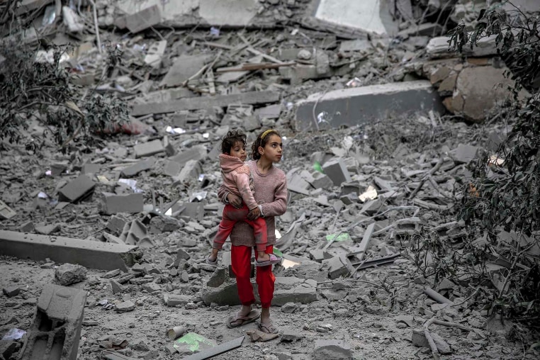 A Palestinian girl carries a child through the rubble of houses destroyed by Israeli bombardment in Gaza City 