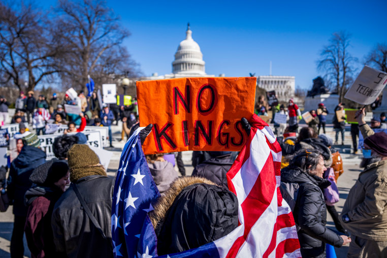 Demonstrators hold signs during the No Kings Day.