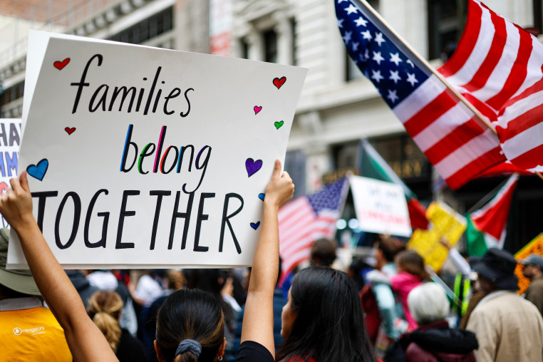 demonstrator carries a sign reading 'Families Belong Together.'