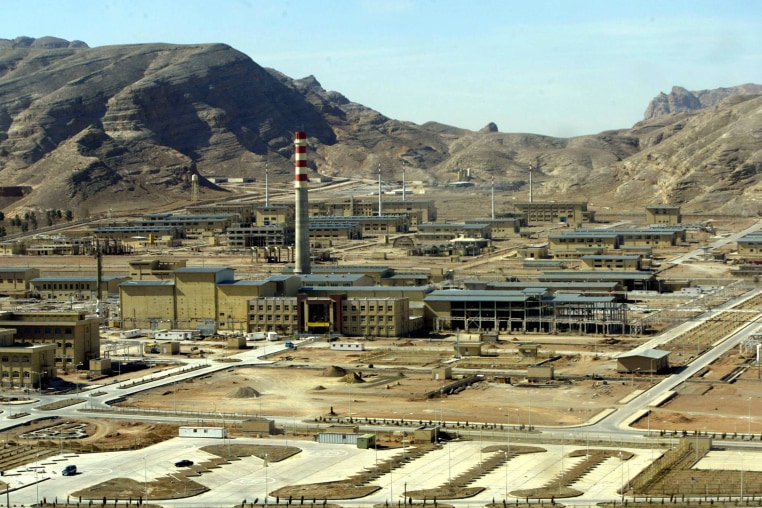 Ground view of a nuclear enrichment facility amidst mountains.
