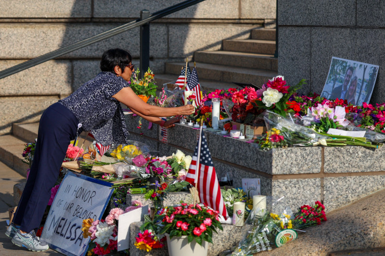 A woman lays flowers at a makeshift memorial.
