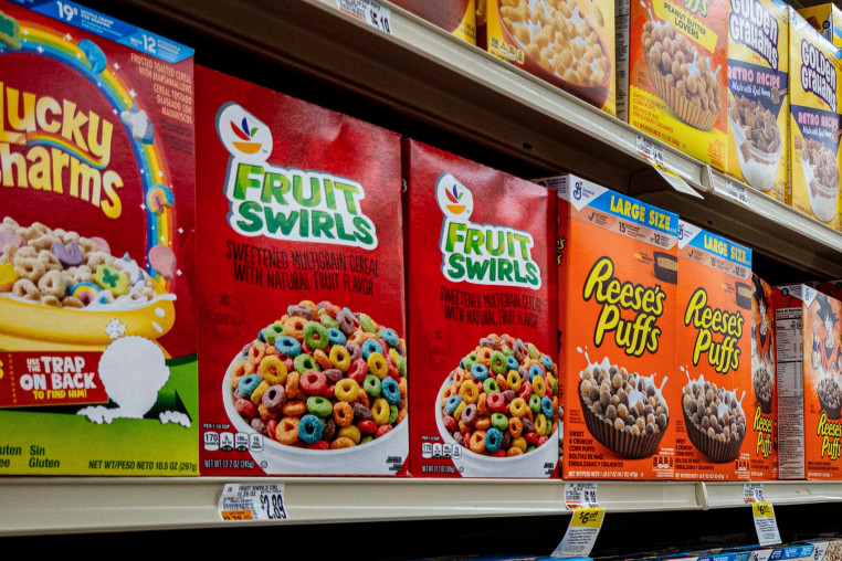 Two boxes of the cereal "Fruit Swirl" next to two boxes of the cereal "Reese's Puffs"