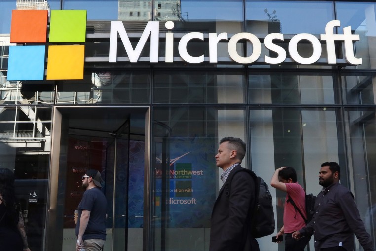 People walk past the front entrance to a Microsoft office building