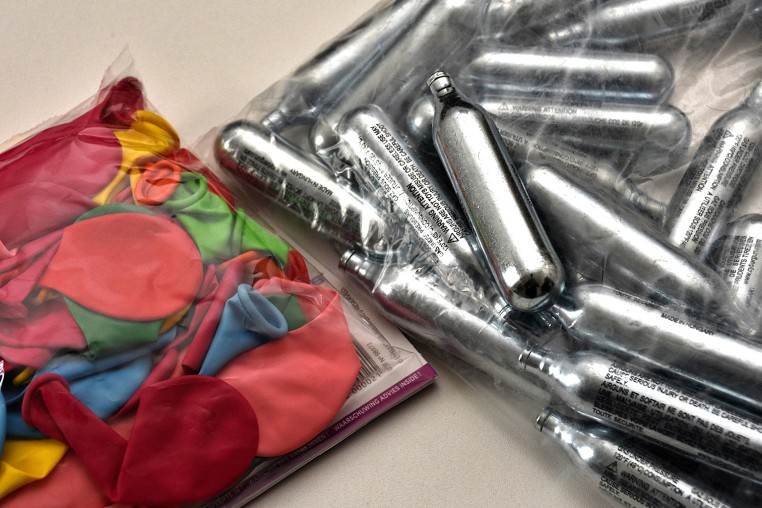 Balloons and nitrous oxide bottles are seen displayed on a table.