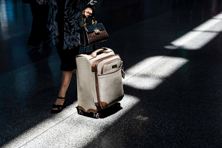 A traveler pushes a suitcase inside of an airport
