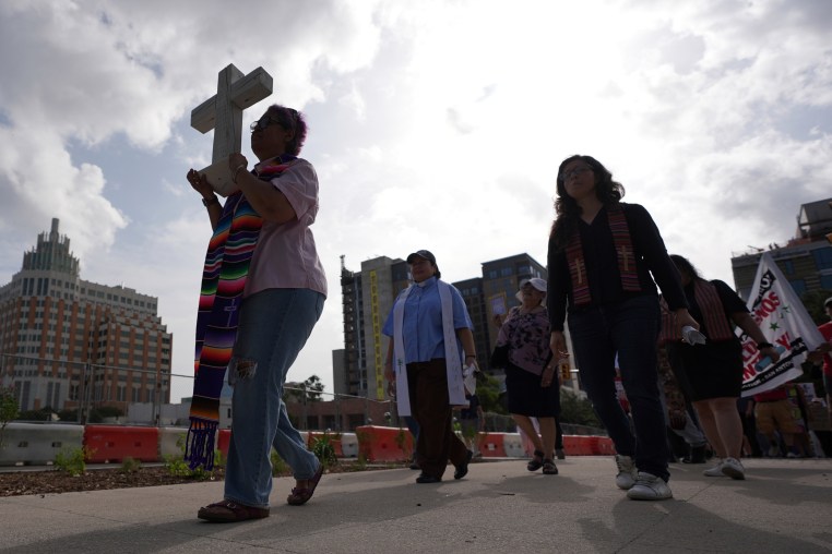 A woman holds a cross as she protests with others.