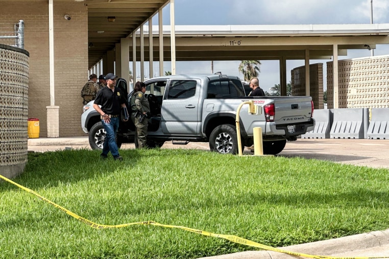 Officials work the scene of a shooting outside, a truck is parked outside with agents surrounding it
