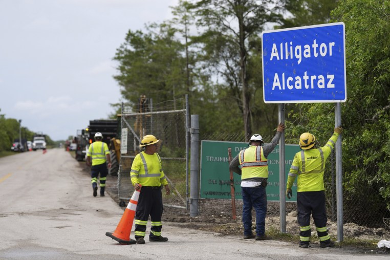 Workers install a sign reading "Alligator Alcatraz" at the entrance to a new migrant detention facility at Dade-Collier Training and Transition facility, Thursday, July 3, 2025, in Ochopee, Fla. 