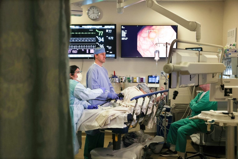 Dr. John Gaetano performs a colonoscopy on Mike Lowe in a hospital room