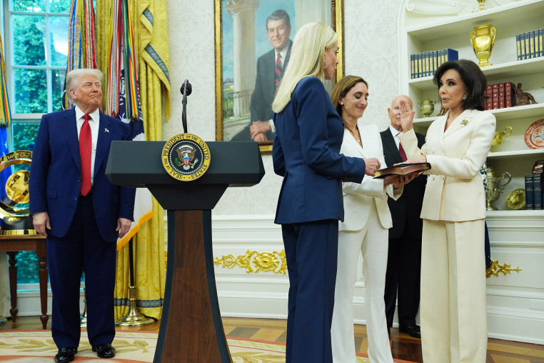 Jeanine Pirro raises her hand during a swearing-in ceremony as President Trump looks on.