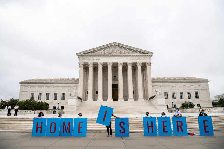People hold signs that read "HOME IS HERE."