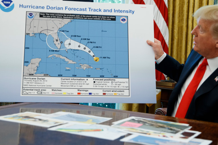 Donald Trump holds a NOAA map,.