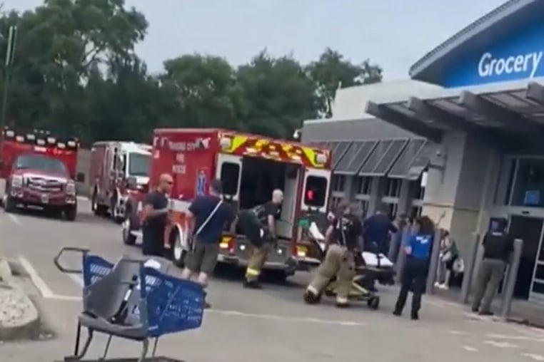 An emergency vehicle has a stretcher in front of it outside of a Walmart location