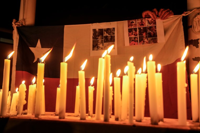 Candles burn during a vigil backdropped with a Chilean national flag and victims of a mine collapse